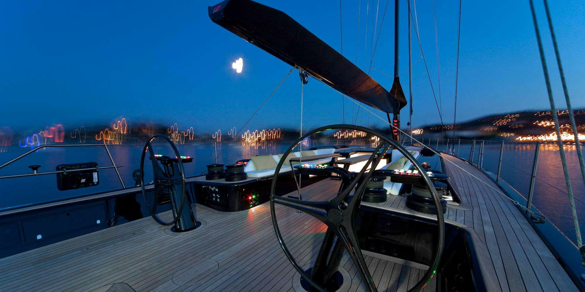 a deck with a large ship and a city at night aboard AESOP Yacht for Charter