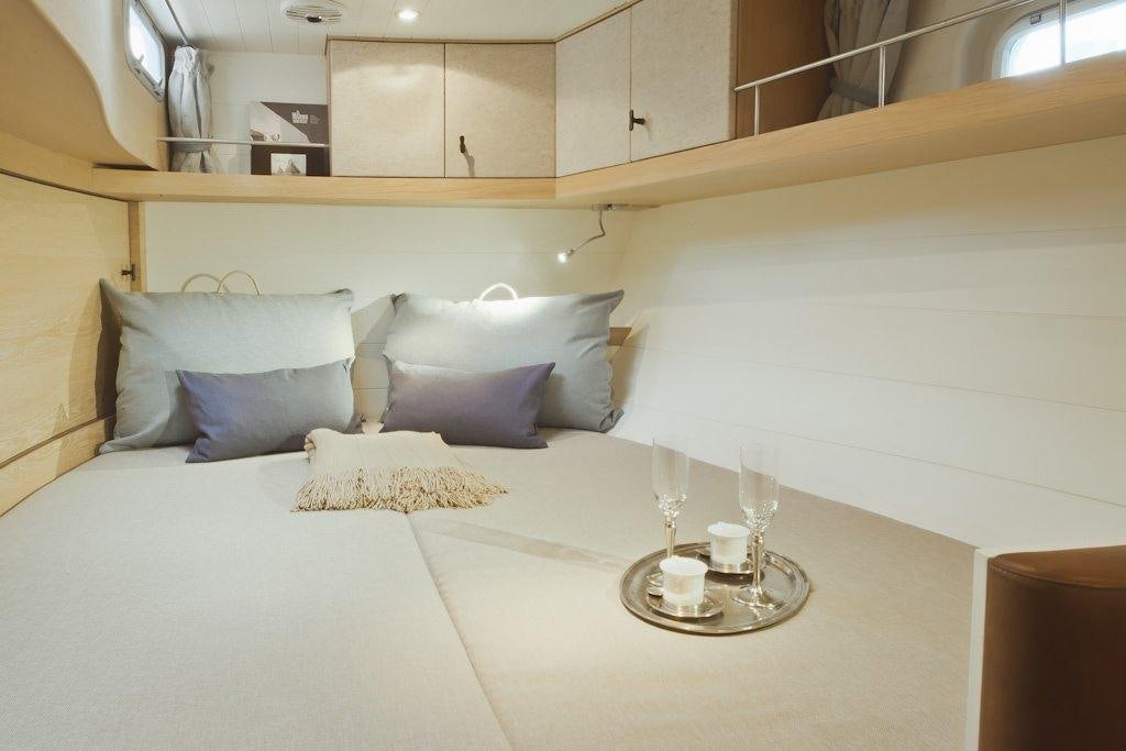 a bed with white sheets and pillows aboard HELENE Yacht for Charter