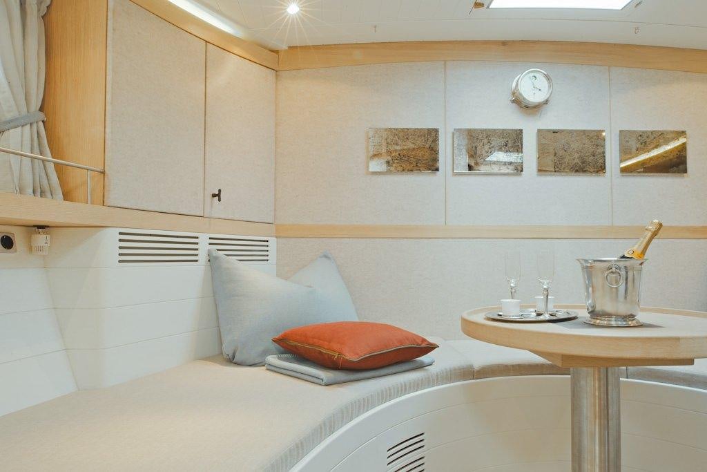 a white bedroom with a bed and a table aboard HELENE Yacht for Charter