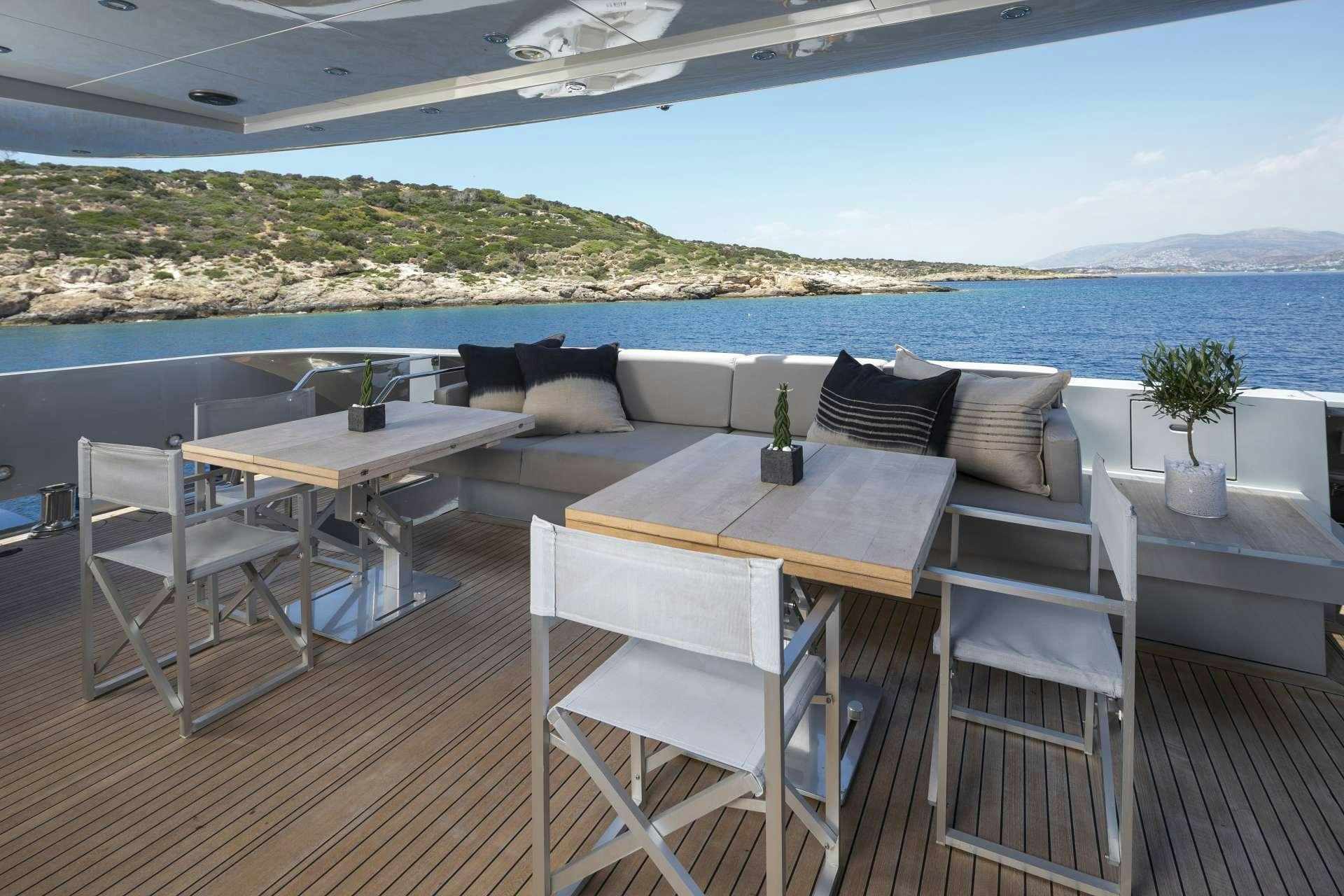 a table and chairs on a deck overlooking a body of water aboard BILLA Yacht for Charter