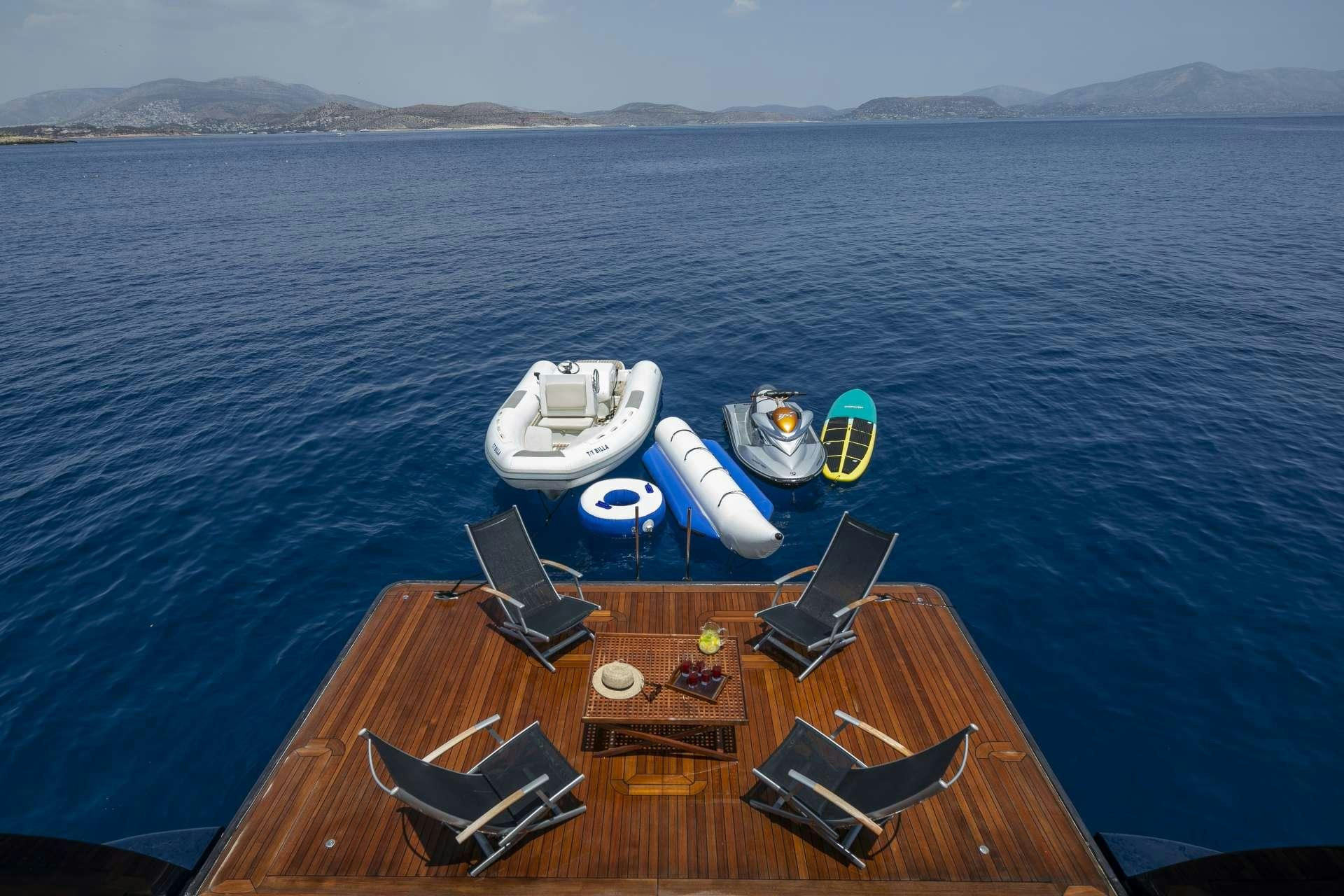 a table with chairs on it next to a body of water aboard BILLA Yacht for Charter