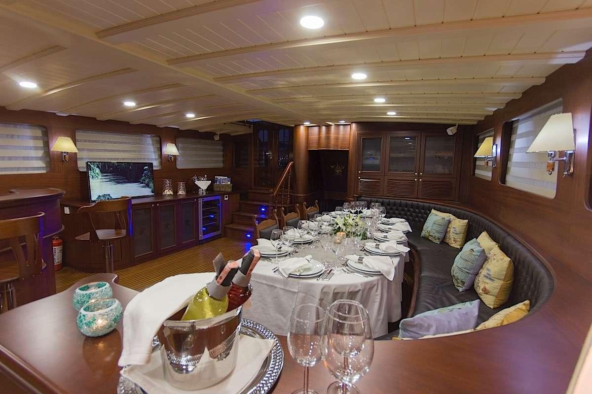 a large room with a table and chairs and a couch aboard PRINCESS KARIA II Yacht for Charter