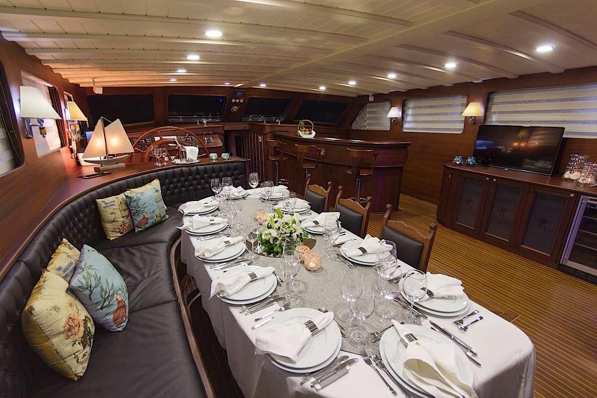 a large dining room with a leather couch and a large wood table aboard PRINCESS KARIA II Yacht for Charter