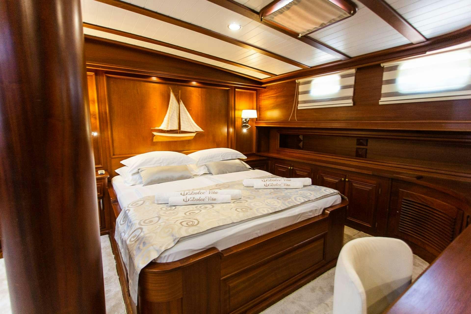 a bed with a white sheet and a wooden headboard aboard DOLCE VITA Yacht for Charter