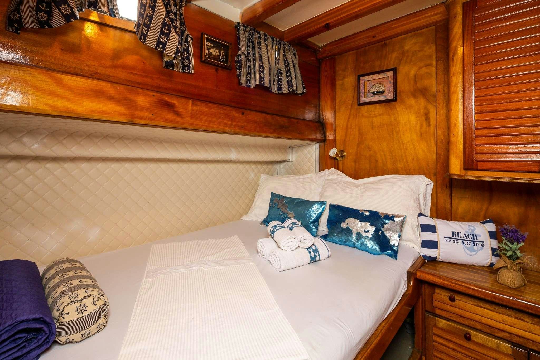 a bed with white sheets and pillows aboard San Yacht for Charter