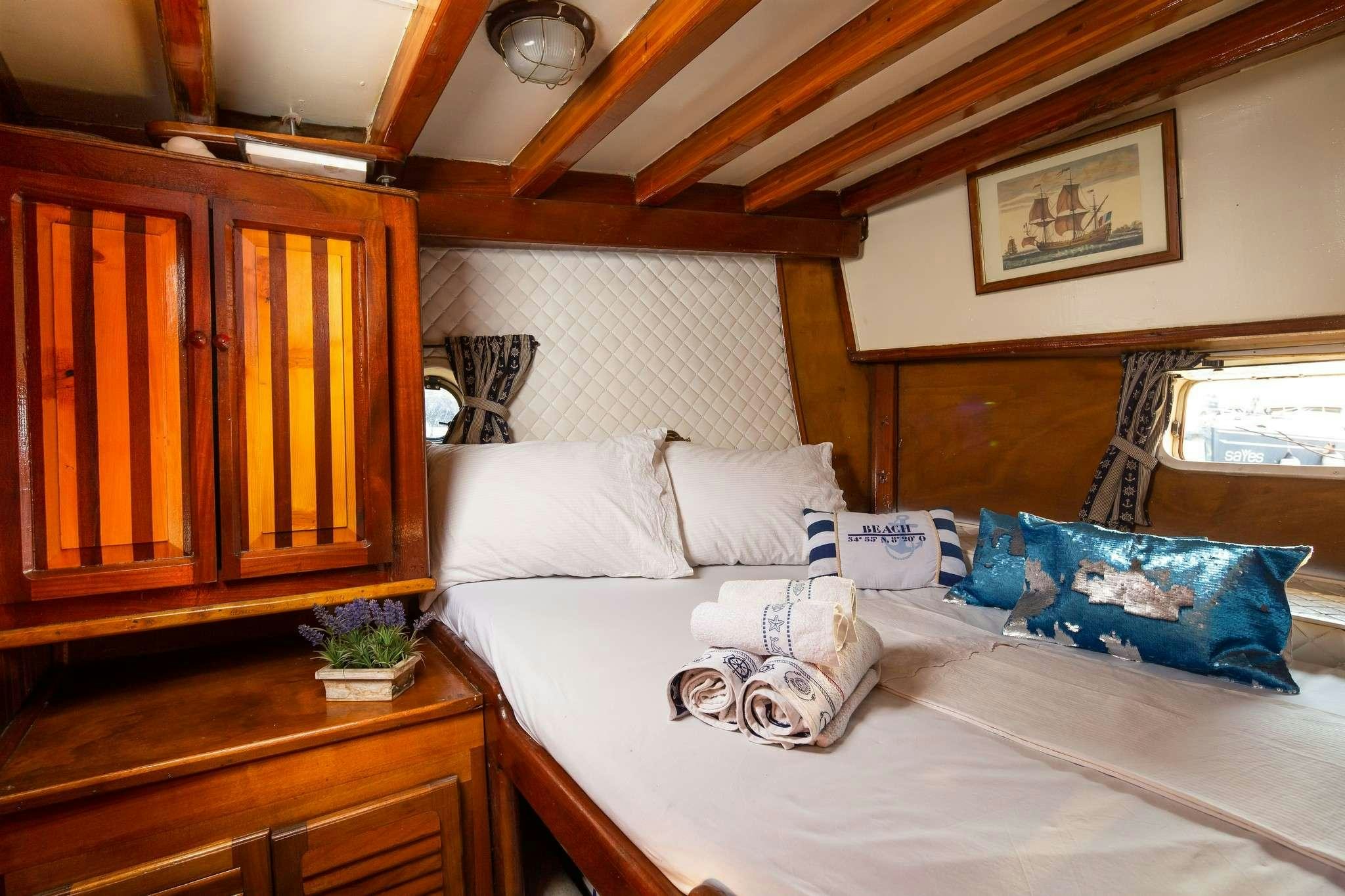 a bed with white sheets and pillows aboard San Yacht for Charter