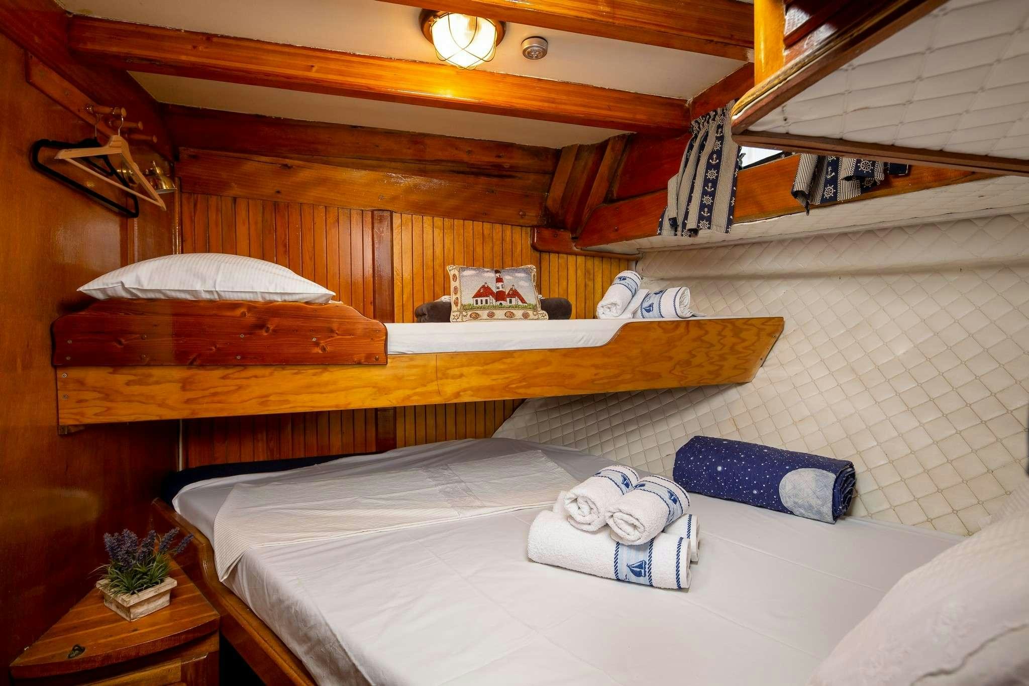 a bed with a white sheet and a wooden headboard aboard San Yacht for Charter