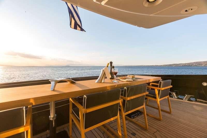 a table and chairs on a deck overlooking a body of water aboard HEESEN Yacht for Charter