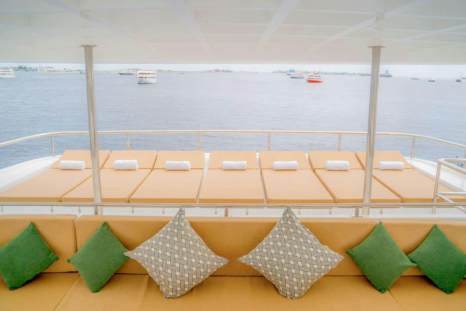 a group of colorful cushions on a deck overlooking a beach aboard ALICE Yacht for Charter
