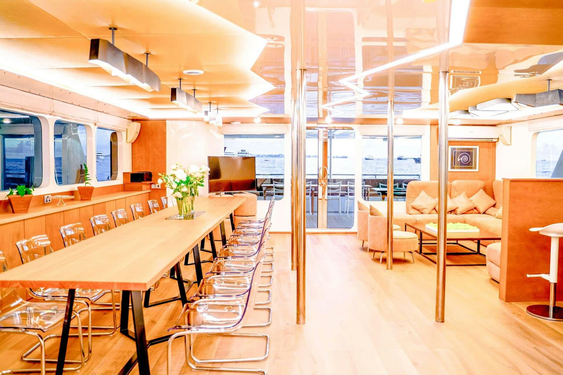 a large room with tables and chairs aboard ALICE Yacht for Charter