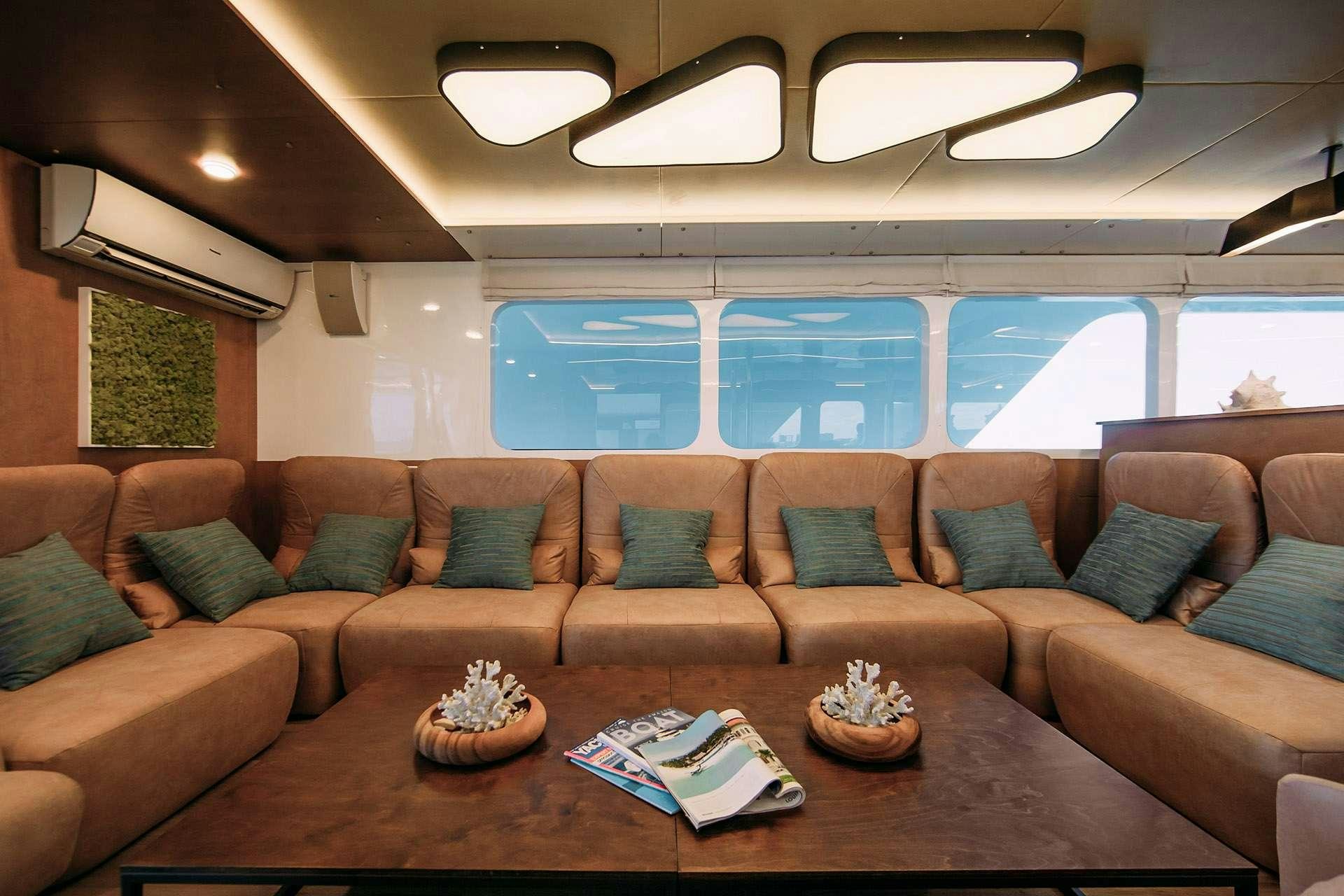 a couch with a coffee table and a glass window aboard ALICE Yacht for Charter