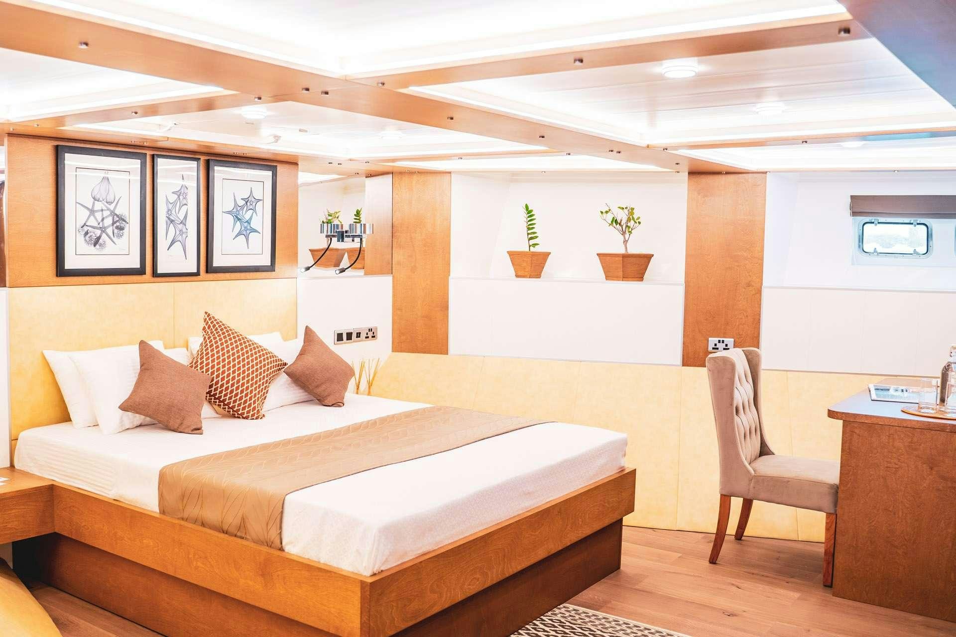 a room with a bed and a chair aboard ALICE Yacht for Charter