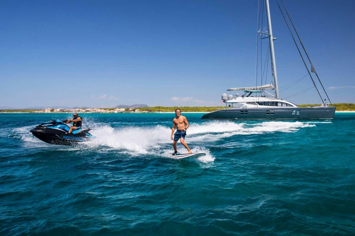 a couple of people surfing in the sea aboard CARTOUCHE Yacht for Charter