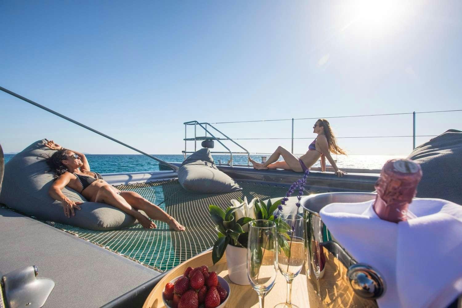 a group of people sitting at a table with a glass of wine and a view of the ocean aboard CARTOUCHE Yacht for Charter