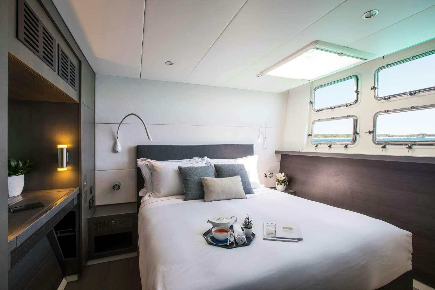 a bed with a white bed spread aboard CARTOUCHE Yacht for Charter