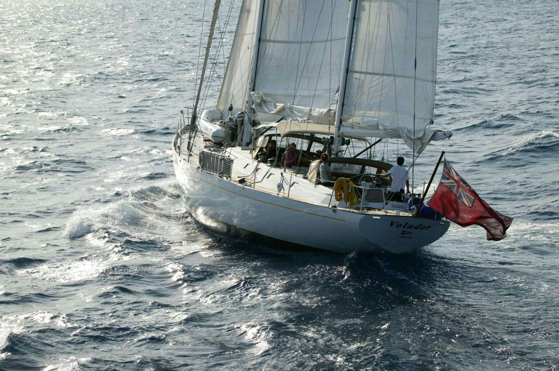 a sailboat with a flag on it aboard VOLADOR Yacht for Charter