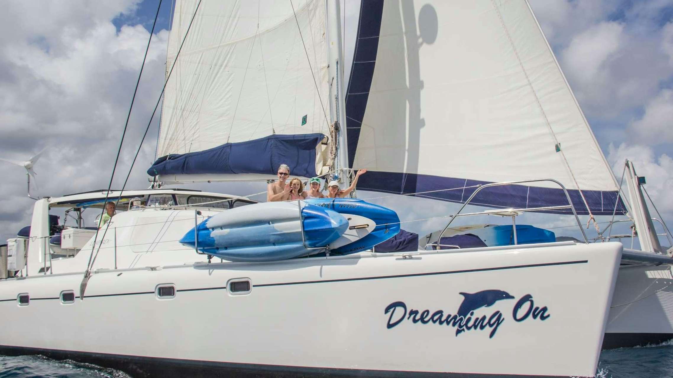 a white boat with a white sail aboard DREAMING ON Yacht for Charter