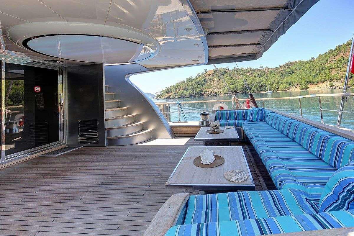 a deck with a table and chairs on it aboard GO Yacht for Charter