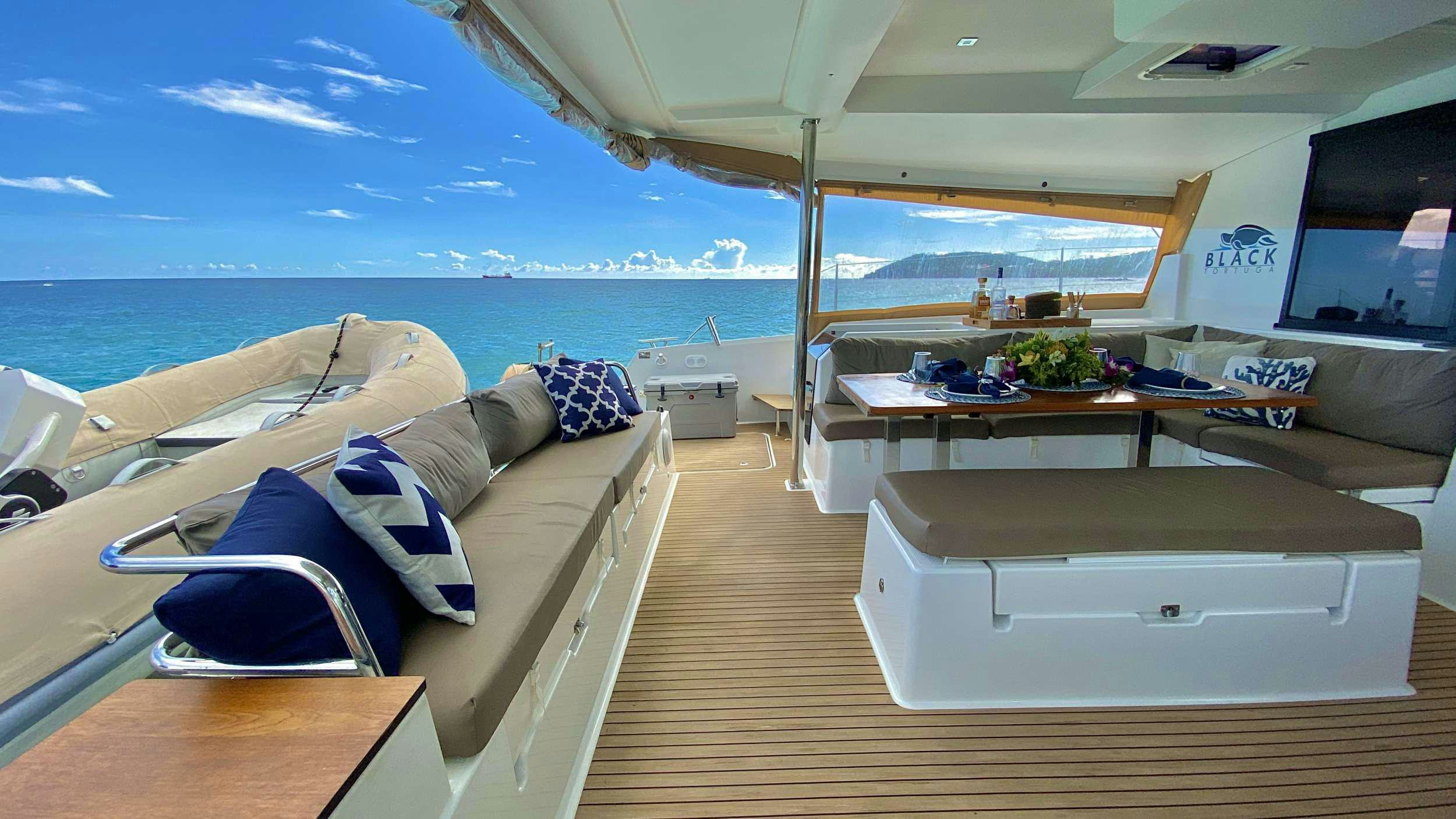 a room with a bed and a table and a large body of water aboard BLACK TORTUGA Yacht for Charter