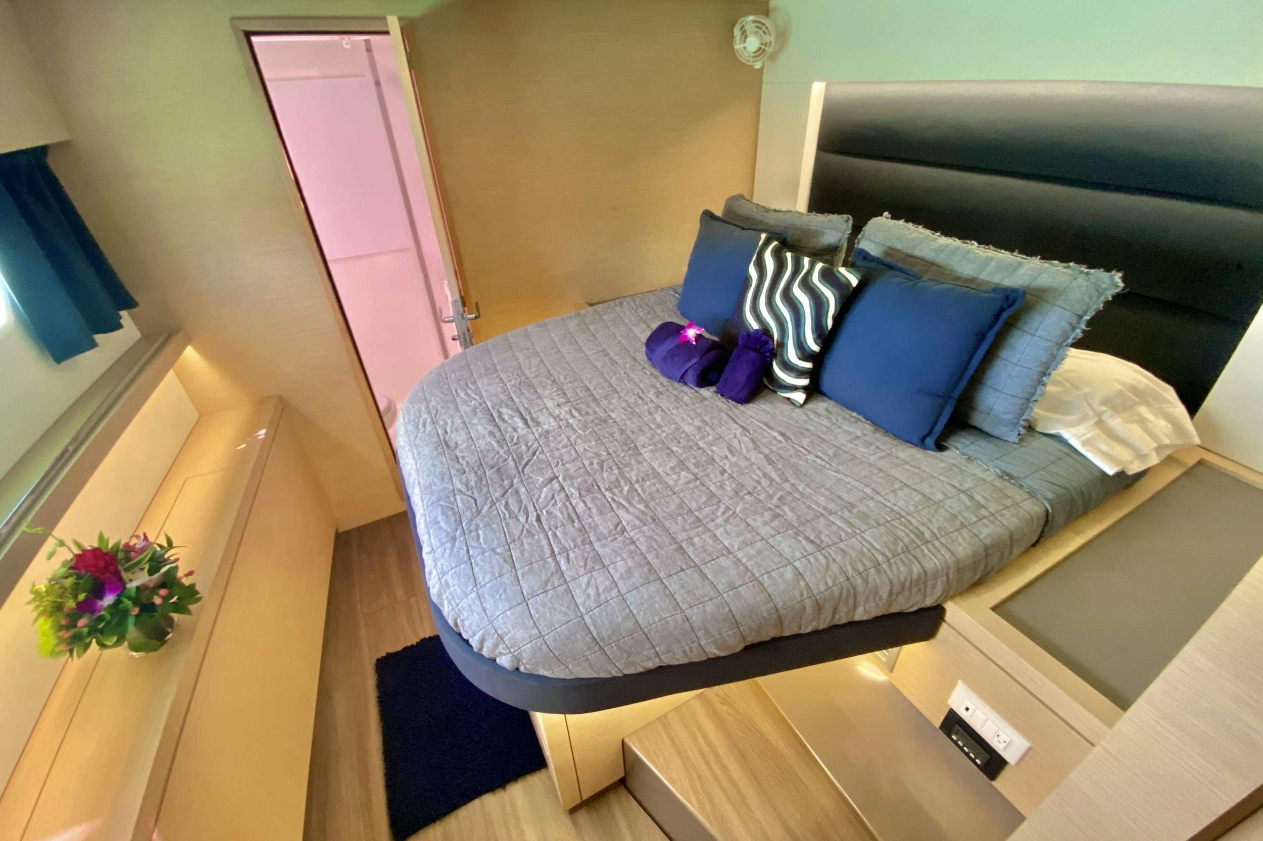 a bed with blue pillows aboard BLACK TORTUGA Yacht for Charter