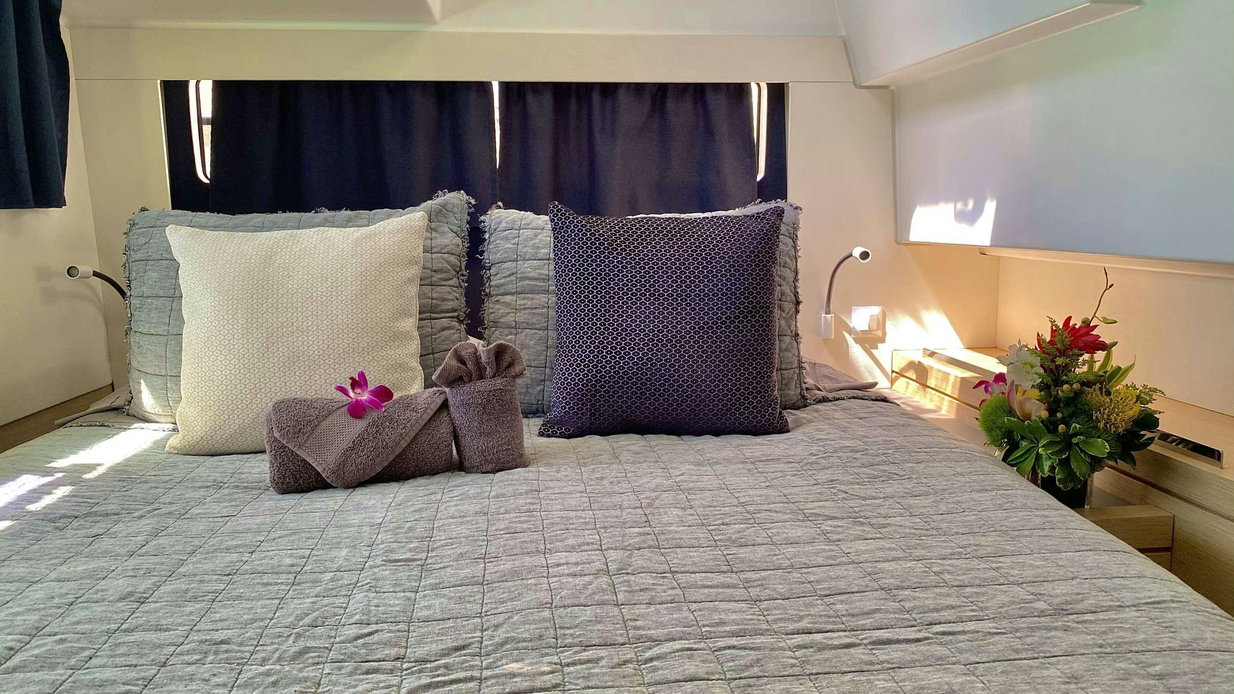 a bed with pillows and flowers aboard BLACK TORTUGA Yacht for Charter