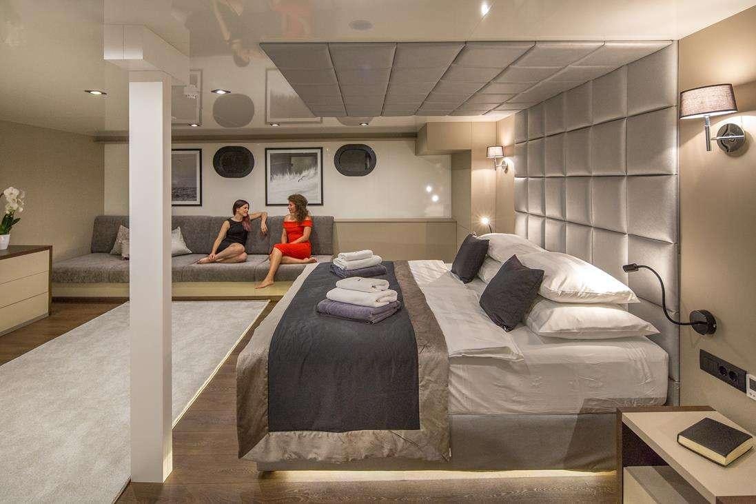 a couple of people sitting on a bed in a room aboard RARA AVIS Yacht for Charter