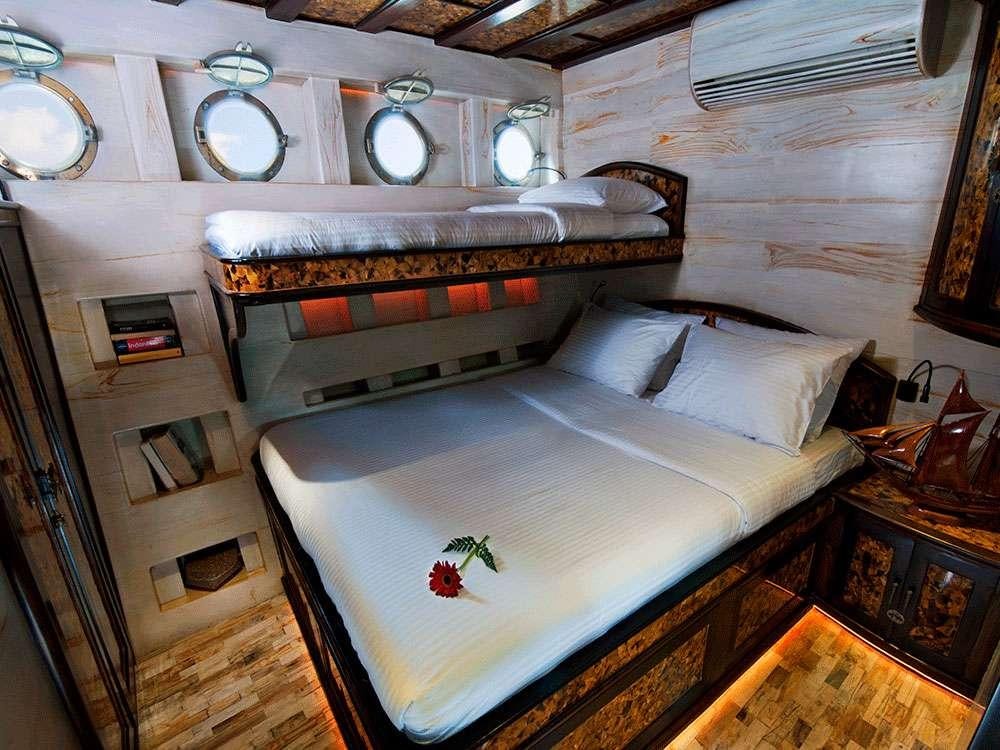 a bed with a white sheet and a round mirror above it aboard MANTAMAE Yacht for Charter