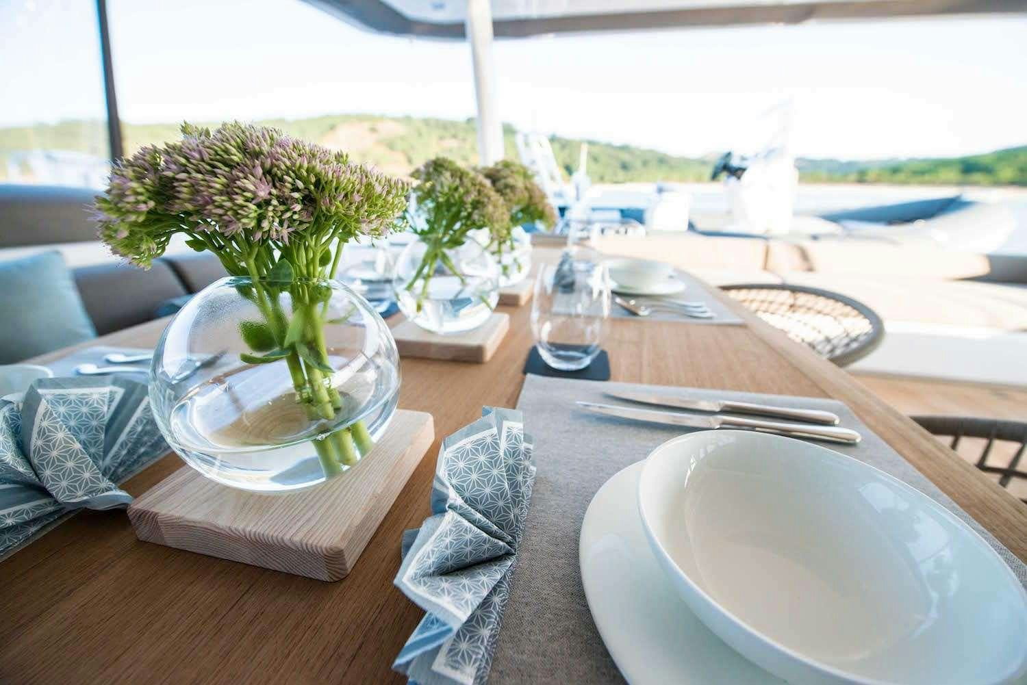 a table with a vase of flowers and a plate of food aboard JOY Yacht for Charter