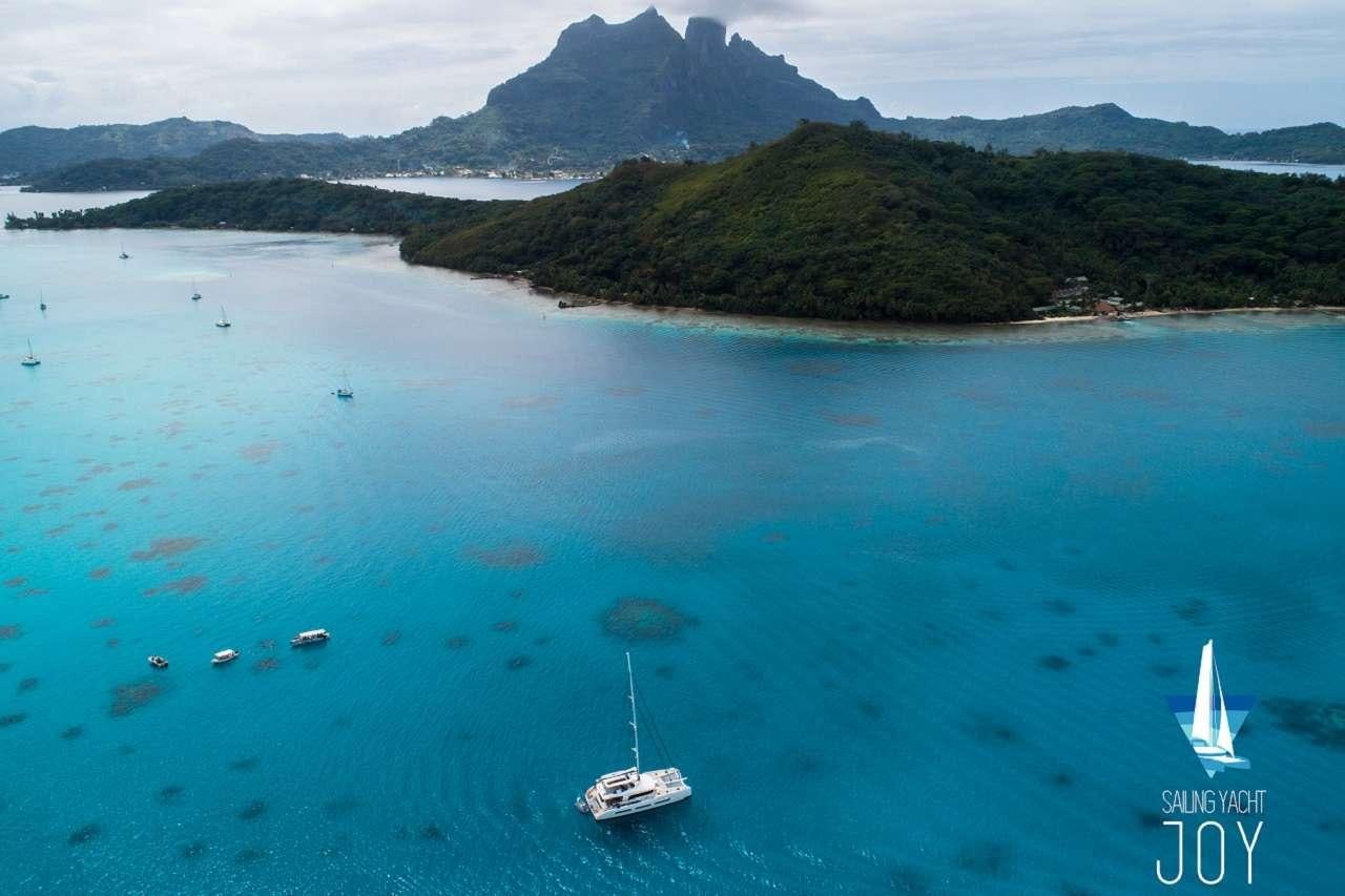 a body of water with boats in it and mountains in the background aboard JOY Yacht for Charter