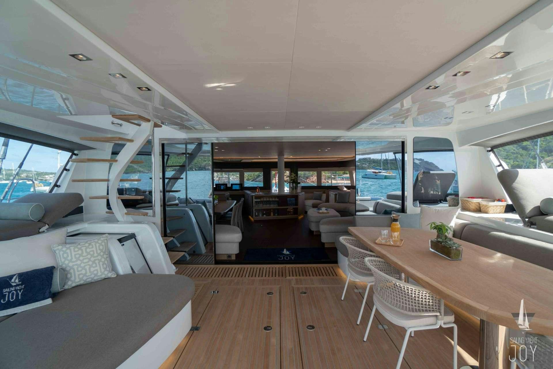 inside of a vehicle with a table and chairs and a couch aboard JOY Yacht for Charter