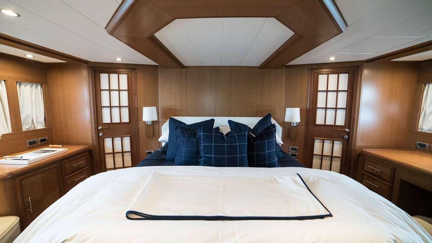 a bed with blue sheets aboard LUMIERE Yacht for Charter