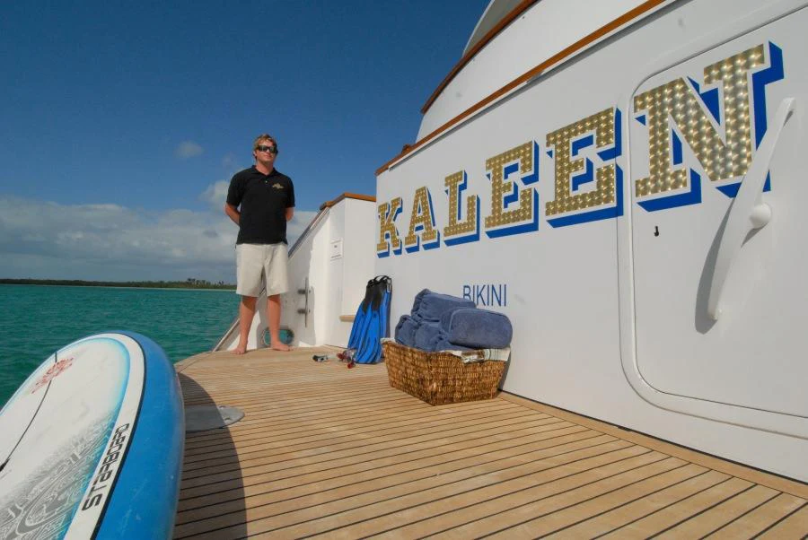 a person standing on a dock next to a boat aboard KALEEN Yacht for Charter