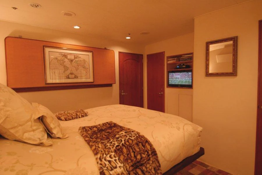 a bedroom with a bed and a tv on the wall aboard KALEEN Yacht for Charter
