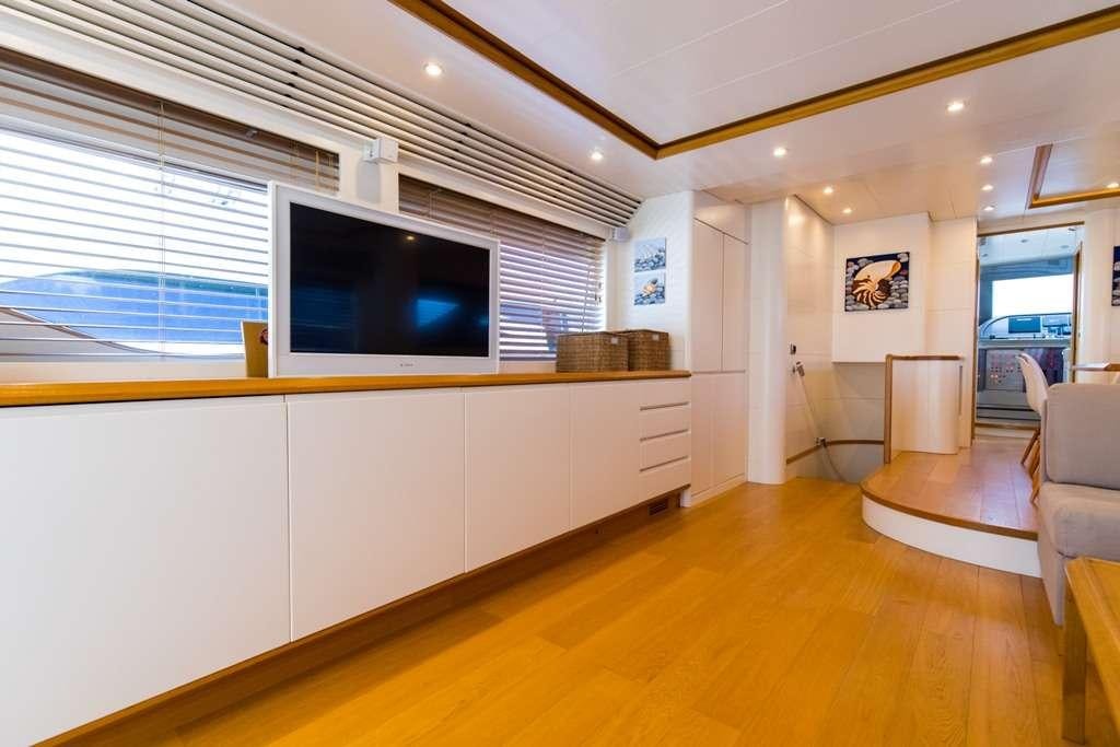 a room with a tv and couch aboard RIVIERA Yacht for Charter
