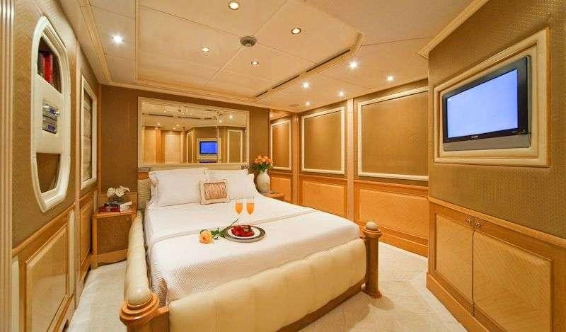 a room with a bed and a television aboard SENSATION Yacht for Charter
