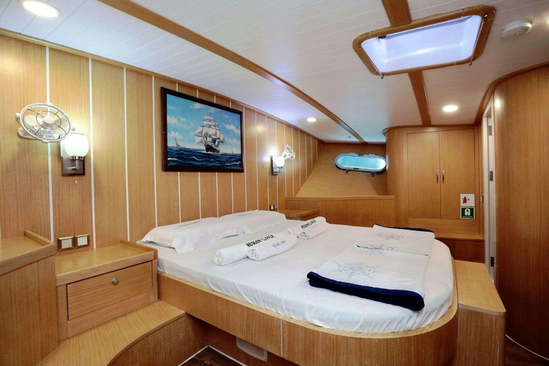 a room with a bed and a television aboard AEGEAN CLIPPER Yacht for Charter
