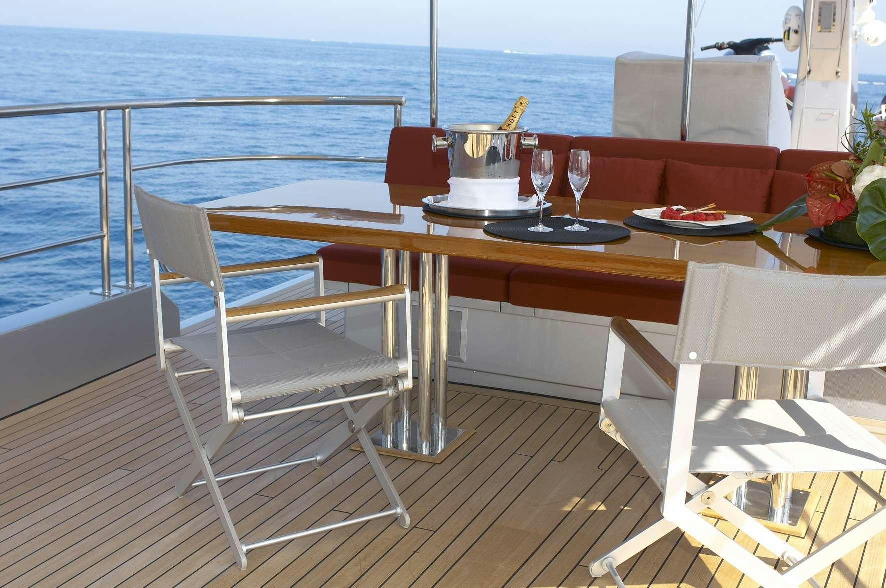 a table with chairs and a large body of water in the background aboard TEMPEST WS Yacht for Charter