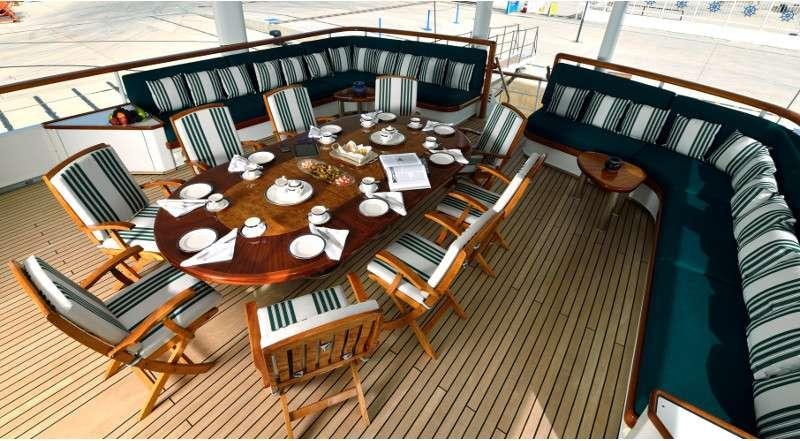 a table with chairs and a piano aboard THE MERCY BOYS Yacht for Charter