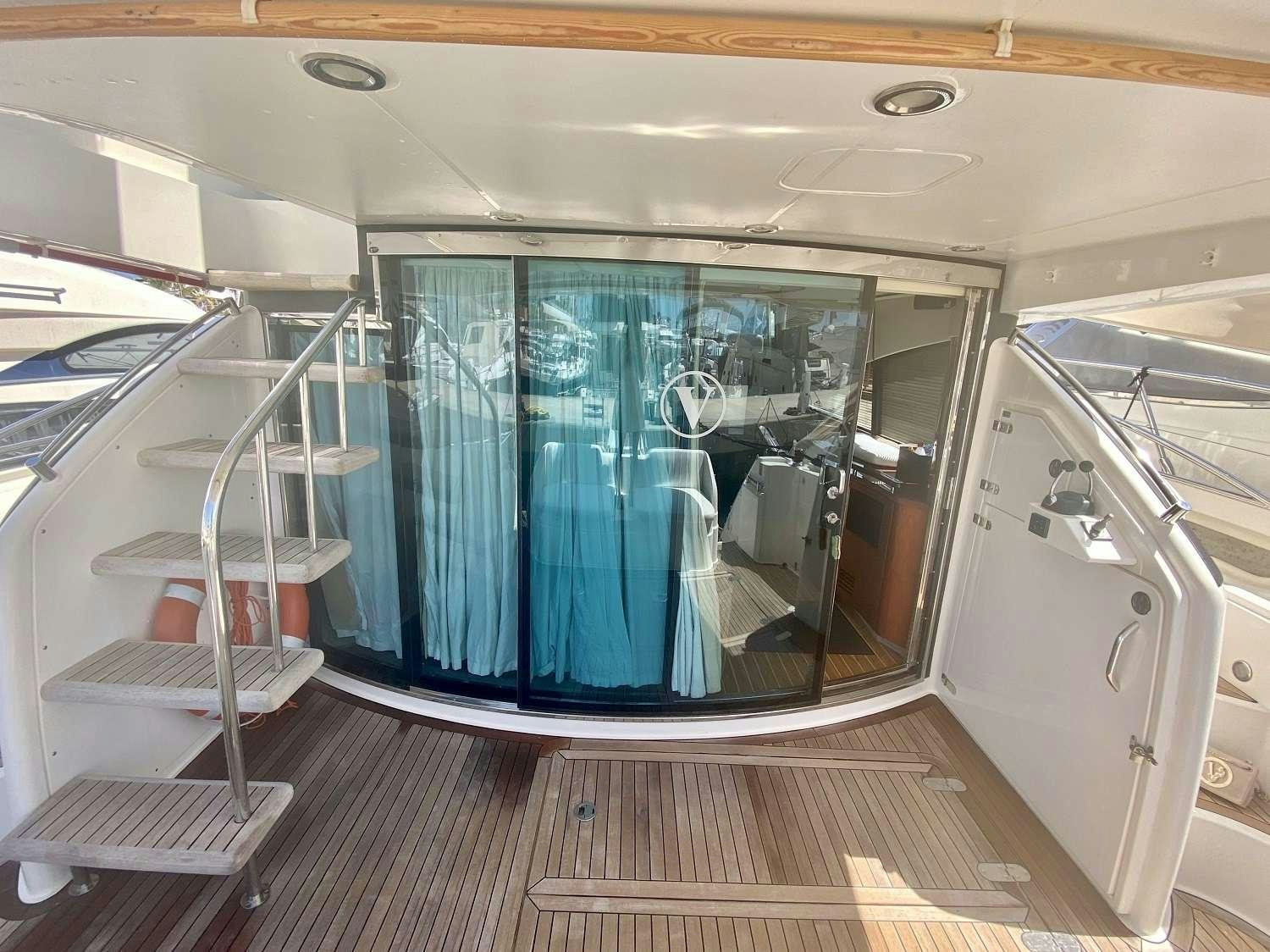 a room with a glass door and a window with a view of the city below aboard VAGABUNDO Yacht for Charter