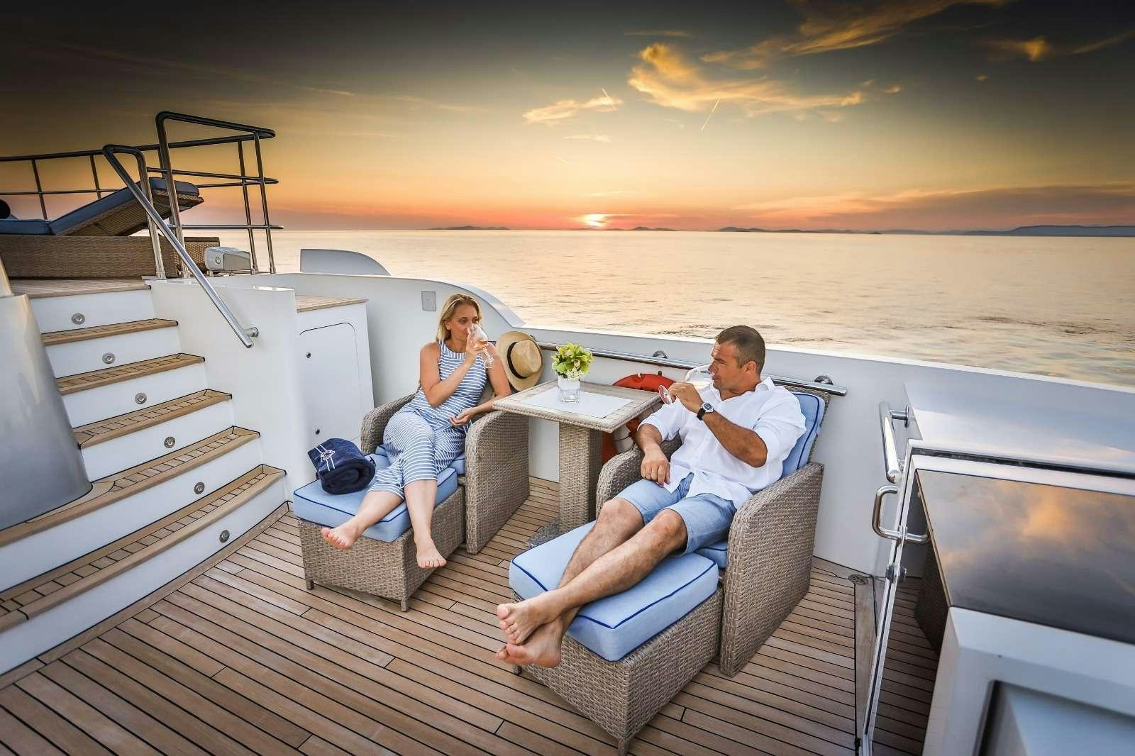 a man and woman sitting on a couch on a boat aboard MILAYA Yacht for Charter