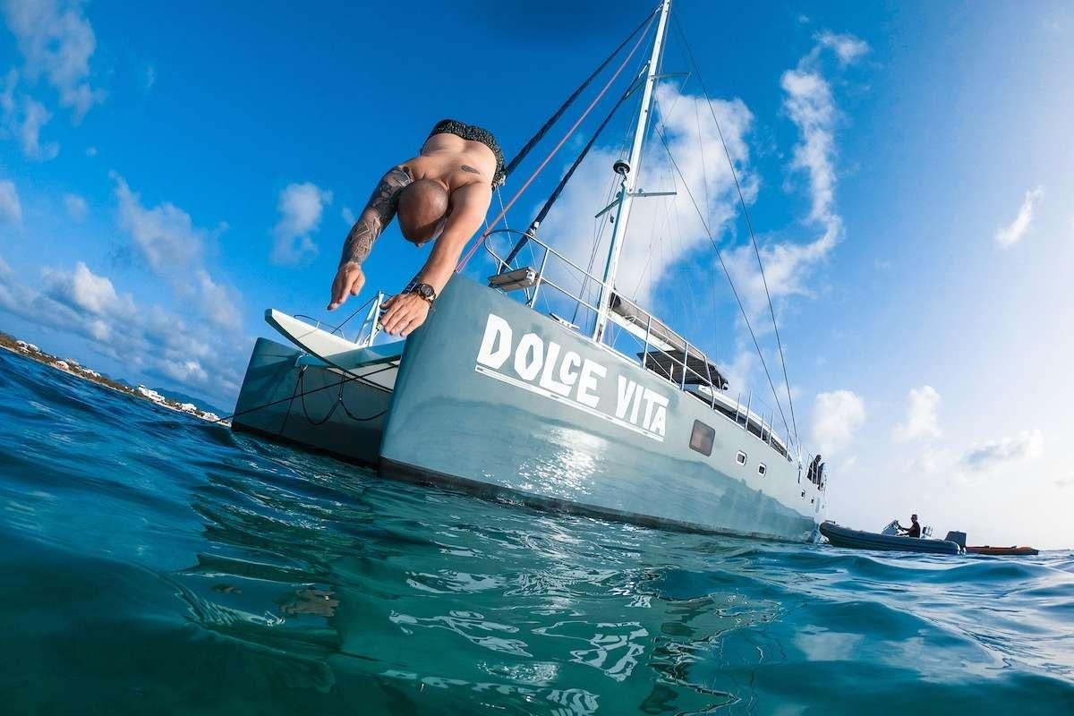 a man jumping off a boat aboard DOLCEVITACAT Yacht for Charter
