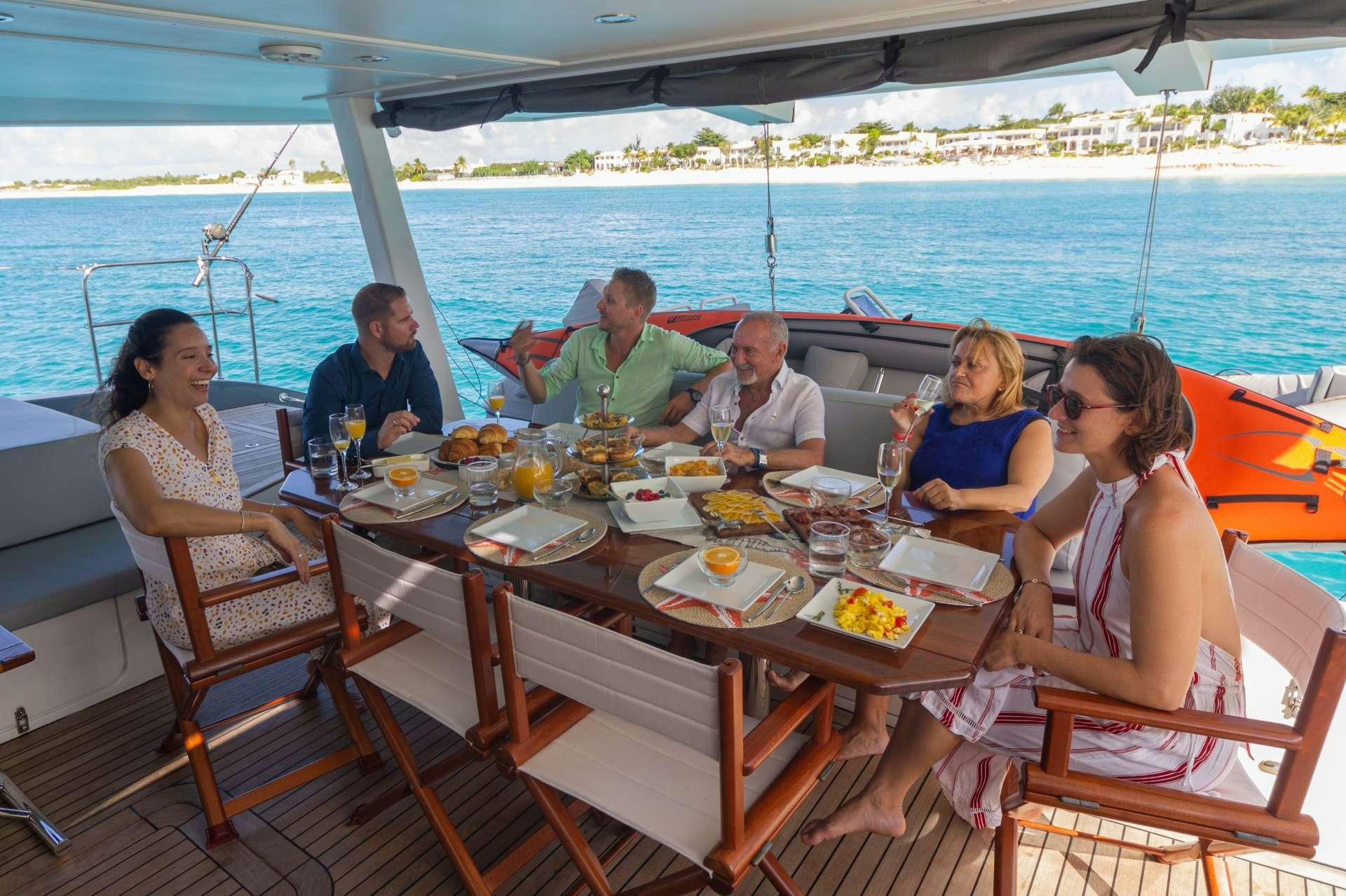 a group of people sitting at a table outside on a boat aboard DOLCEVITACAT Yacht for Charter
