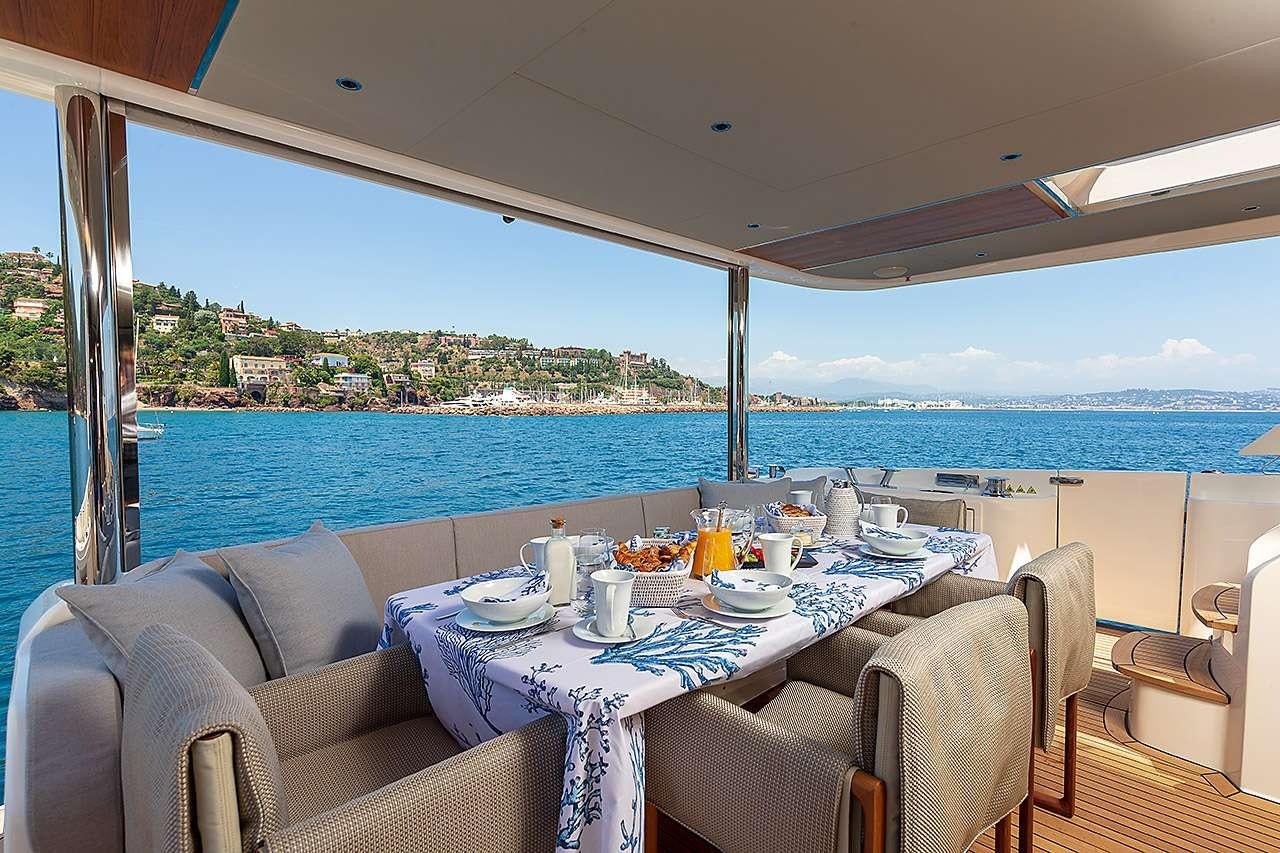 a table set for a meal on a deck overlooking a large body of water aboard ENIGMA Yacht for Charter