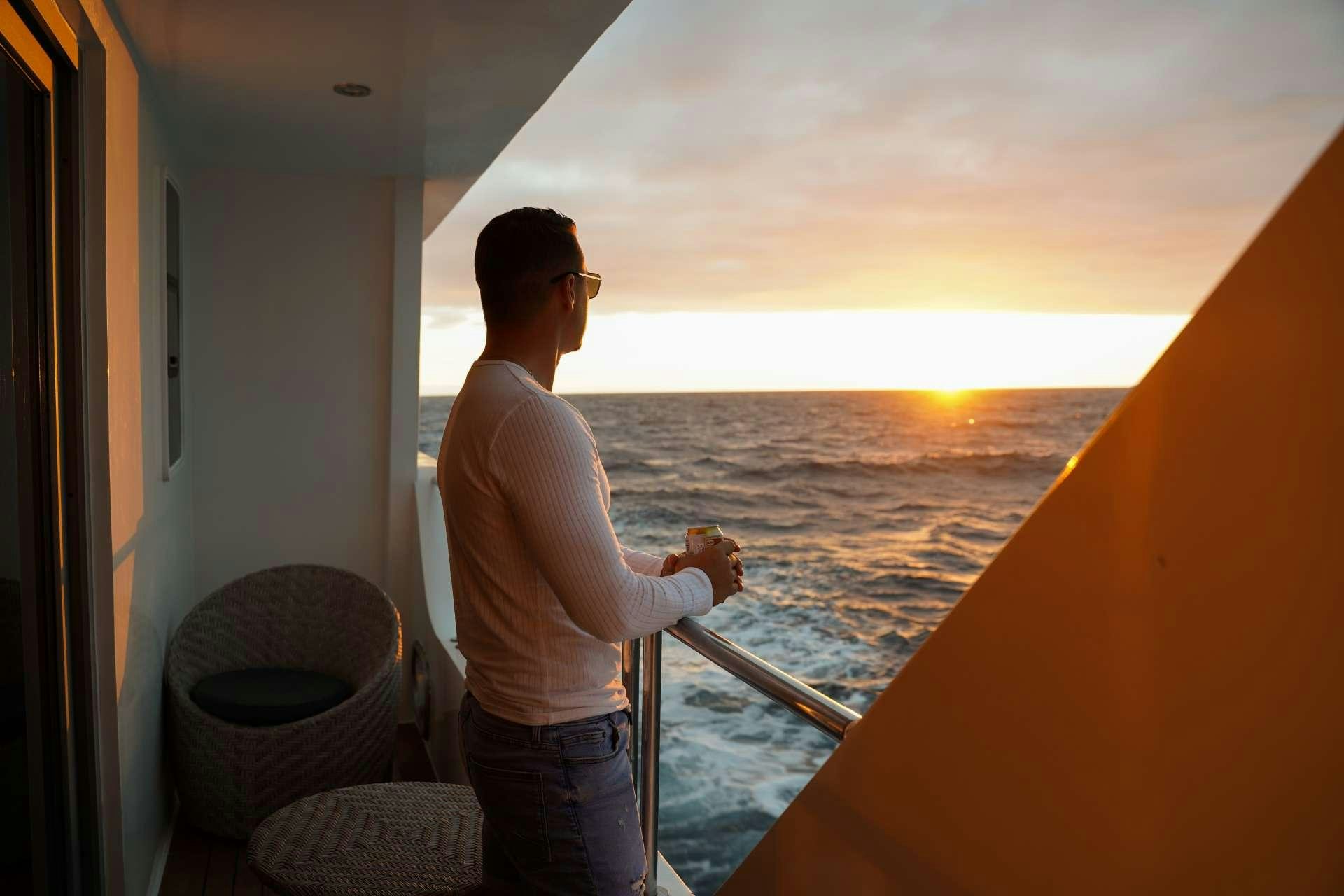 a person standing on a balcony overlooking the ocean aboard INFINITY Yacht for Charter