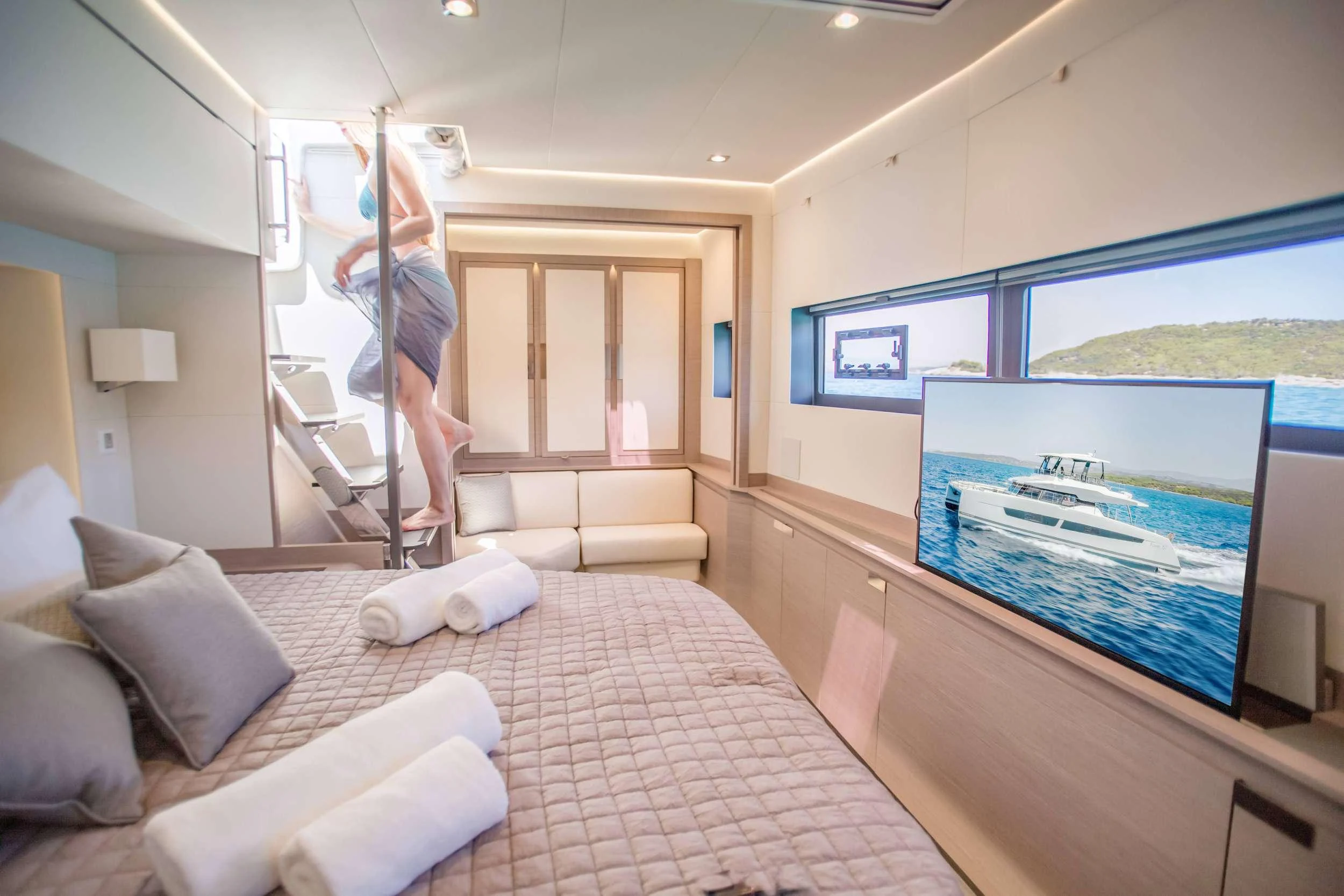 a person standing on a ladder in a room with a bed and a tv aboard CHRISTAL MIO Yacht for Charter