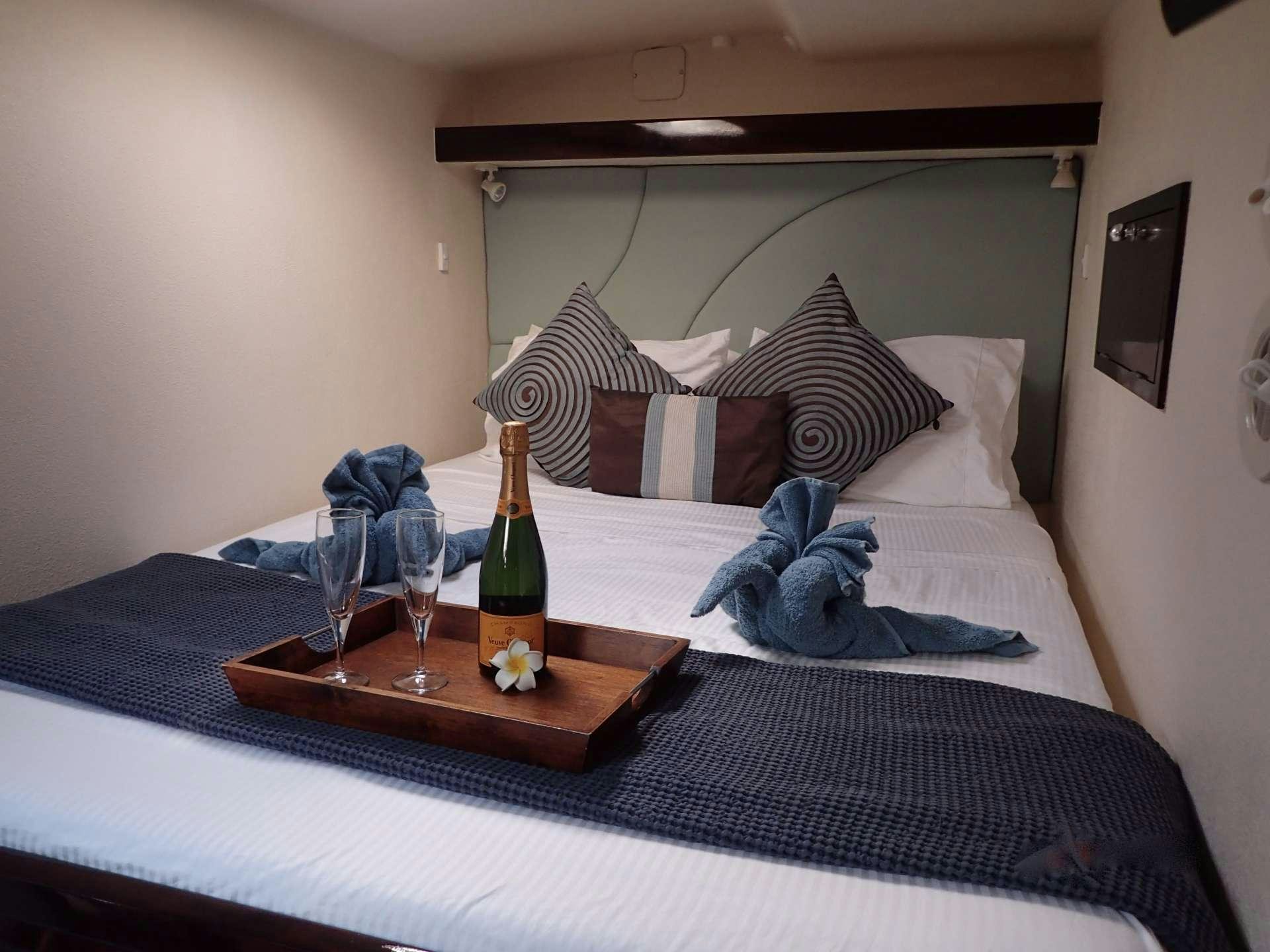 a bottle of wine and glasses on a bed aboard NUTMEG Yacht for Charter