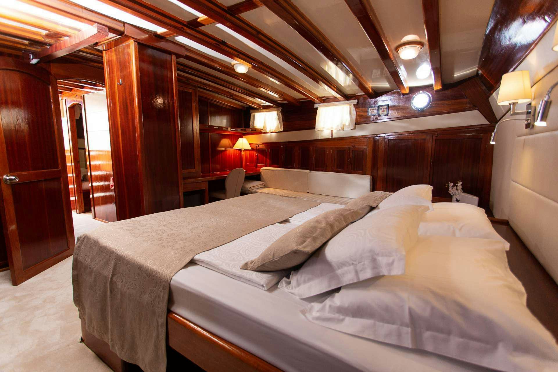 a bed with white sheets aboard KADENA Yacht for Charter