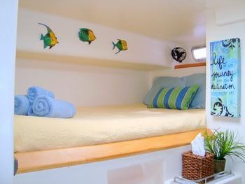 a bed with a white pillow and a plant on the side aboard FEEL THE MAGIC Yacht for Charter