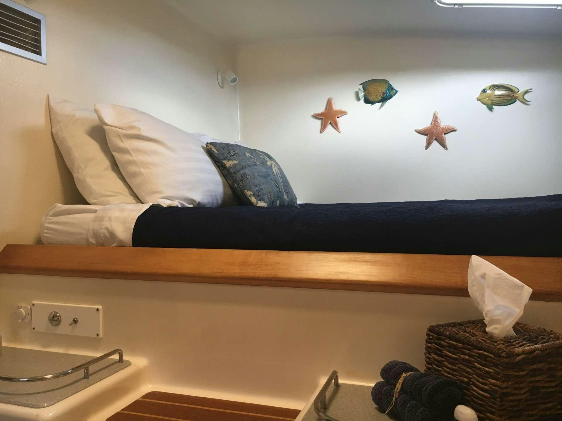 a bed with a blue pillow and a black pillow with a white wall and a black pillow with aboard FEEL THE MAGIC Yacht for Charter