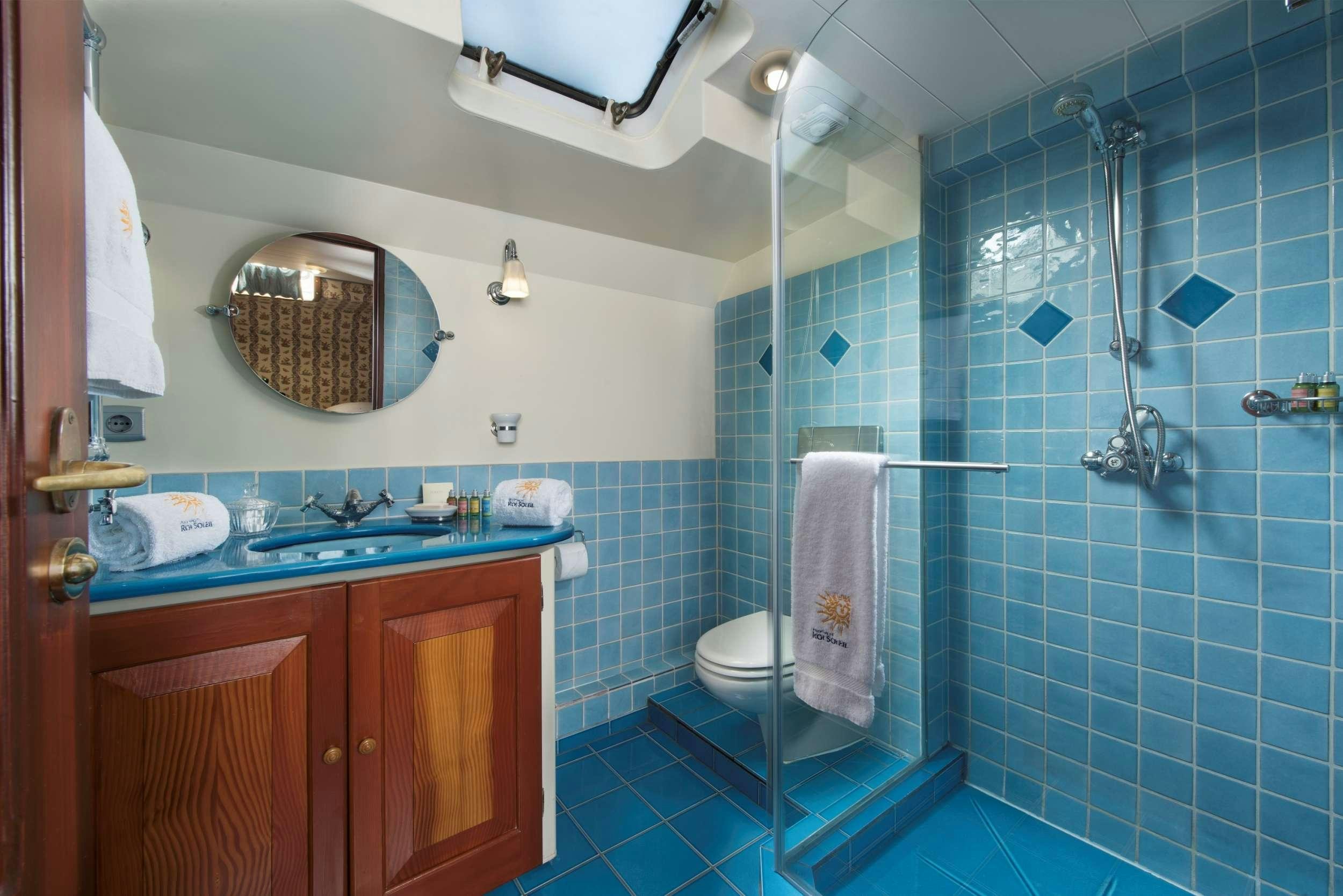 a bathroom with a blue tile floor aboard ROI SOLEIL Yacht for Charter